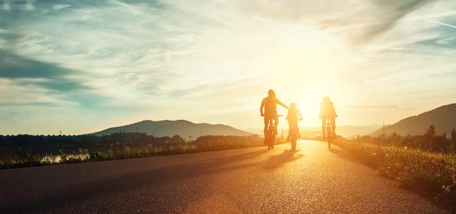 family cycling into sunset